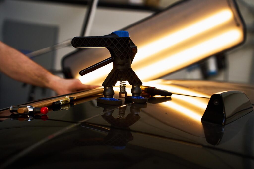 Technician performing mobile paintless dent repair